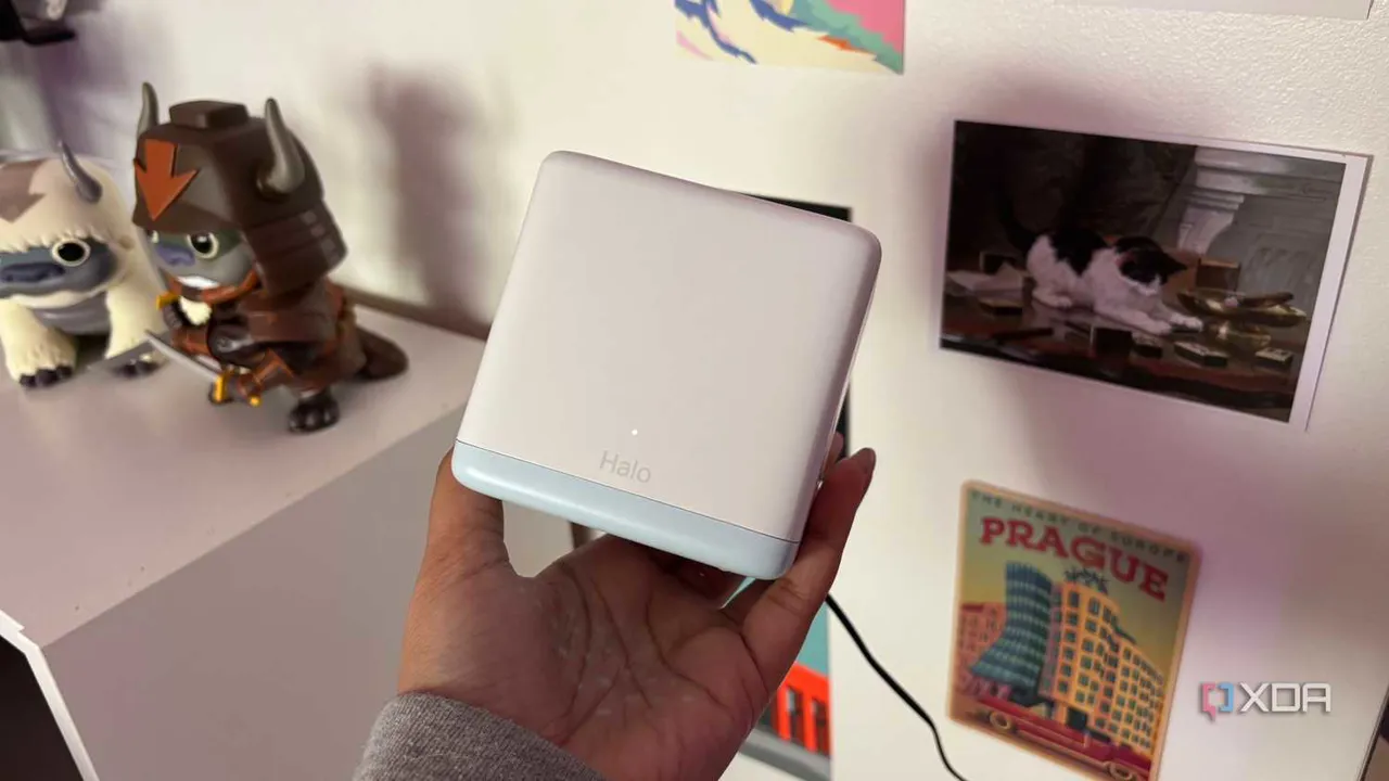 Kartpostalların bulunduğu duvarın önünde Mercusys mesh Wi-Fi sistemi düğümü