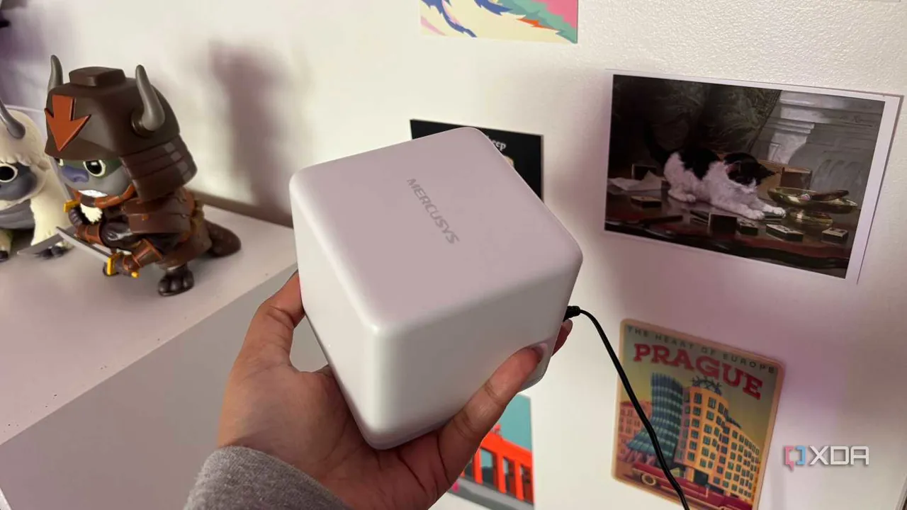 Kartpostallar önünde üstten görünen Mercusys mesh Wi-Fi sistemi düğümü