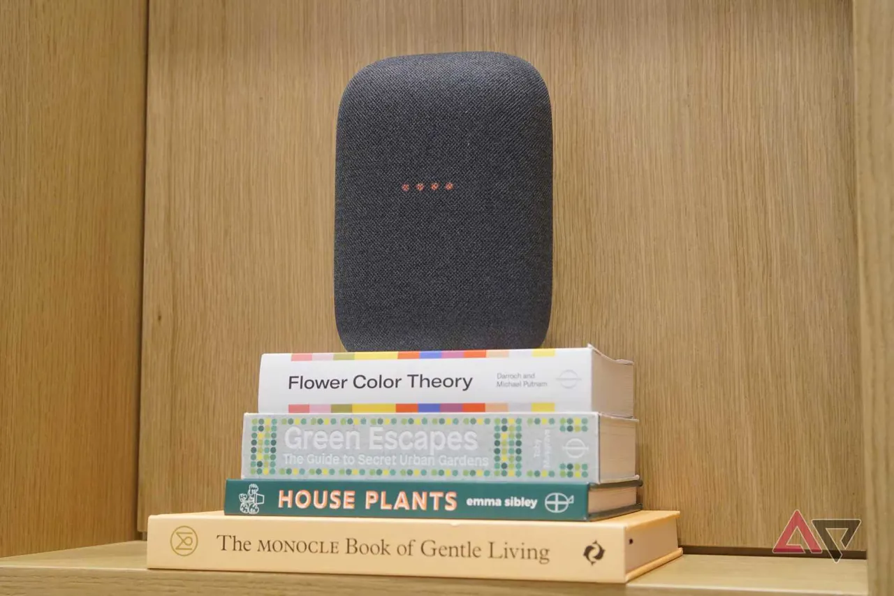 A Google Nest Audio smart speaker in gray, sat atop a stack of books.
