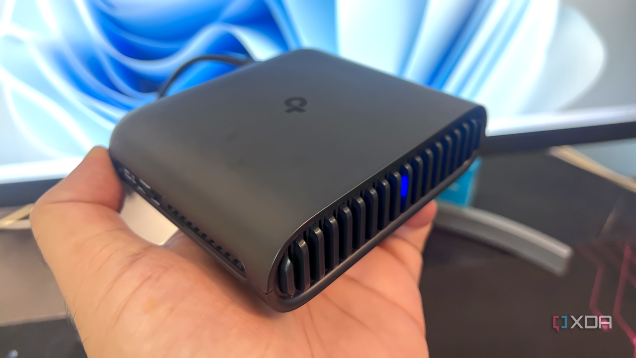 small travel router being held up in front of a monitor