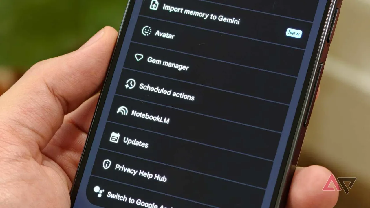 A hand holding a smartphone showing the Google Gemini settings list highlighting the Scheduled Actions option below Gem manager
